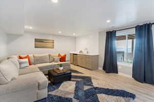 Living area featuring wet bar, light wood-style flooring, and recessed lighting