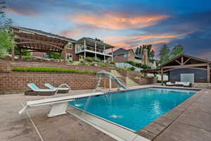 View of swimming pool with a water slide, a pergola, a patio area, and an outdoor hangout area