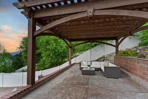 Patio terrace at dusk featuring a patio area, an outdoor living space, a pergola, and a fenced backyard