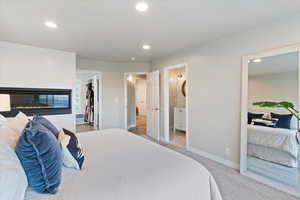 Bedroom with recessed lighting, a spacious closet, carpet floors, connected bathroom, and a glass covered fireplace