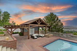 Pool at dusk with an outdoor living space with a fire pit, a gazebo, and a patio area