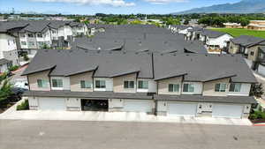 Exterior space featuring stone siding, a garage, a residential view, and a mountain view