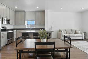 Kitchen with appliances with stainless steel finishes, dark countertops, wood finished floors, and recessed lighting