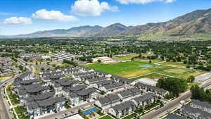 Aerial view of property and surrounding area featuring mountains and nearby suburban area