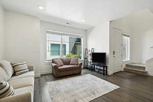 Living area featuring plenty of natural light, dark wood-style flooring, stairway, and recessed lighting