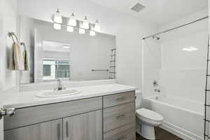 Full bath featuring vanity, washtub / shower combination, and wood finished floors