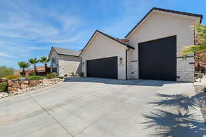 View of front of property with an attached garage, stone siding, stucco siding, and concrete driveway