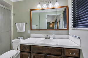 Full bath with vanity, an enclosed shower, and ornamental molding