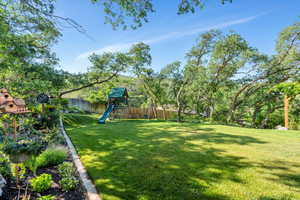 Fenced backyard featuring a playground