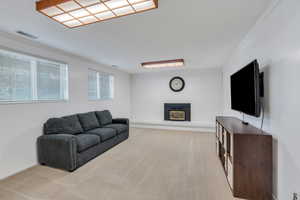 Living area with light carpet, a fireplace, and ornamental molding