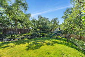 Fenced backyard featuring a playground