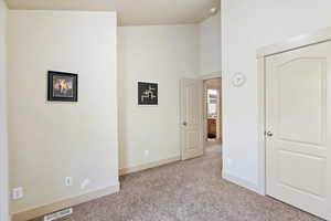 Unfurnished bedroom with light carpet and a towering ceiling