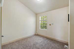 Spare room featuring lofted ceiling and carpet flooring