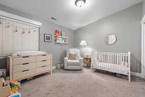 Bedroom featuring light colored carpet and a crib