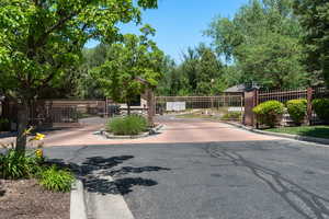 View of asphalt street with curbs, a gate, and a gated entry