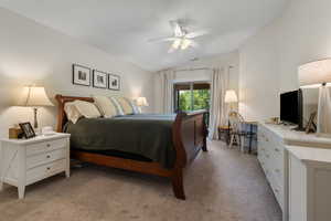 Bedroom with lofted ceiling, light colored carpet, an office area, and a ceiling fan