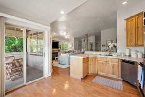 Kitchen with dishwasher, open floor plan, a peninsula, light wood-style floors, and vaulted ceiling