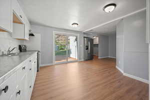 Kitchen with appliances with stainless steel finishes, decorative backsplash, light wood-style flooring, white cabinetry, and light countertops