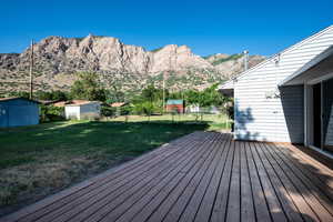 Wooden deck featuring a fenced backyard, a shed, and a mountain view