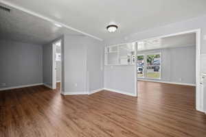 Unfurnished living room with wood finished floors and a textured ceiling