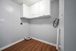 Laundry area featuring hookup for an electric dryer, washer hookup, dark wood finished floors, cabinet space, and a textured ceiling