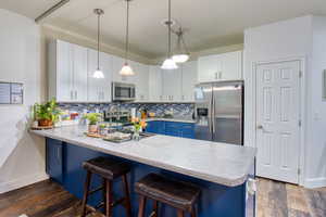 Kitchen with stainless steel appliances, dark wood-style floors, a peninsula, and light countertops