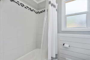 Bathroom with shower / bathtub combination with curtain and ornamental molding