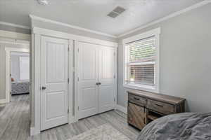 Bedroom featuring light wood-style flooring and crown molding