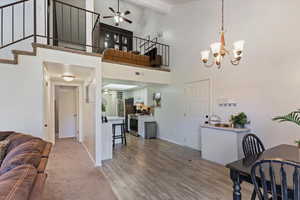 Living room featuring a ceiling fan, a chandelier, stairs, beamed ceiling, and high vaulted ceiling