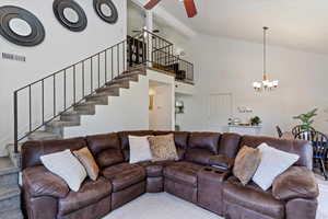 Living area featuring stairs, ceiling fan, a chandelier, high vaulted ceiling, and beamed ceiling