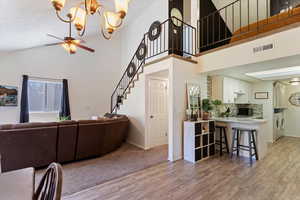 Living room featuring washer and dryer, light wood-style floors, a chandelier, a ceiling fan, and stairway
