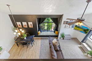 Living area with a textured ceiling, wood finished floors, and a ceiling fan