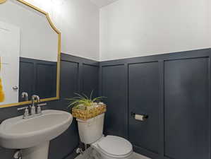 Half bathroom with a decorative wall and wainscoting.