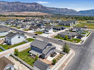 Aerial perspective of suburban area featuring a mountain backdrop and corner lot with RV parking as well as a neighborhood bike trail.