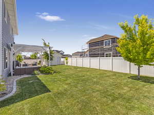Fenced backyard featuring a storage unit, a pergola, an outdoor hangout area, and a residential view