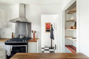Kitchen with  stainless steel gas range oven, wooden counters, tile patterned floors, and cabinetry