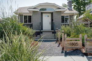 View of front of home featuring brick siding, a chimney, and entry steps