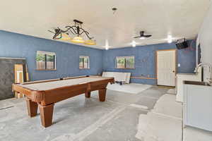 Rec room with concrete flooring, pool table, washer / dryer, and a ceiling fan