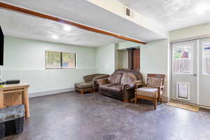 Living area with finished concrete floors, a wood stove, and a textured ceiling