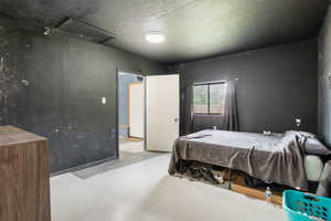 Bedroom featuring finished concrete floors and attic access