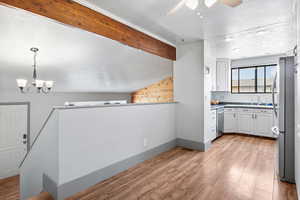 Kitchen featuring appliances with stainless steel finishes, white cabinetry, a ceiling fan, a chandelier, and light wood-style floors