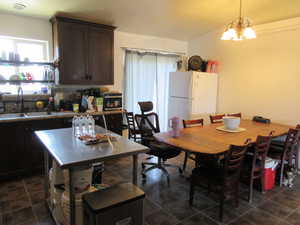 Kitchen with freestanding refrigerator, dark brown cabinetry,  and decorative light fixtures