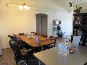 Dining space with arched walkways, a chandelier, and lofted ceiling