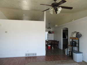 Living room with lofted ceiling, ceiling fan, a textured ceiling, and wood finished floors