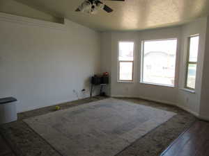 Spare room featuring a ceiling fan, wood finished floors, and a textured ceiling, bay window.