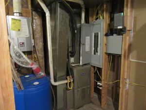 Utility room featuring electric panel and tankless water heater
