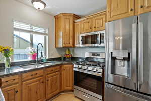Kitchen featuring stainless steel appliances, dark stone countertops, and light wood finished floors