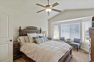 Bedroom with lofted ceiling, light carpet, and ceiling fan