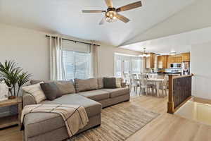 Living area with a chandelier, lofted ceiling, light wood-style flooring, and ceiling fan