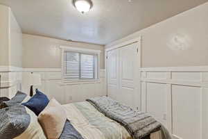 Bedroom with a wainscoted wall, a decorative wall, and a closet